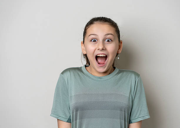 Portrait of a little surprised girl with her mouth open looking to the side on a gray background. High quality photo