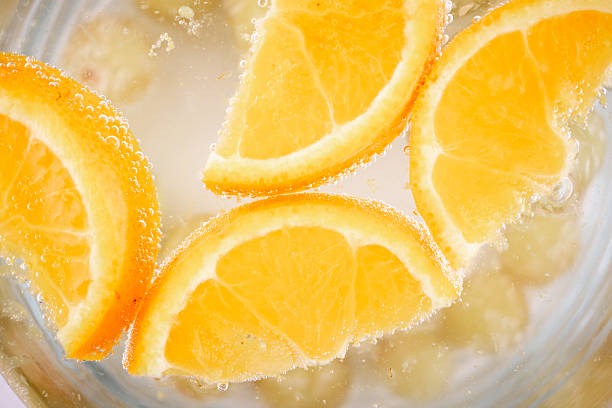 Capture pure, refreshing vitality! This inviting close-up features vibrant orange slices gracefully suspended in sparkling water, evoking a sense of healthy hydration and invigorating freshness. Ideal for beverage, wellness, or healthy recipe content