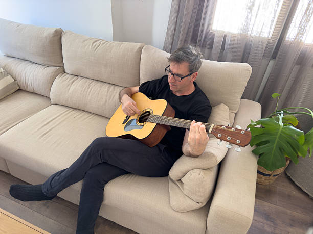 istock Musician playing acoustic guitar at home on the sofa 2217820368