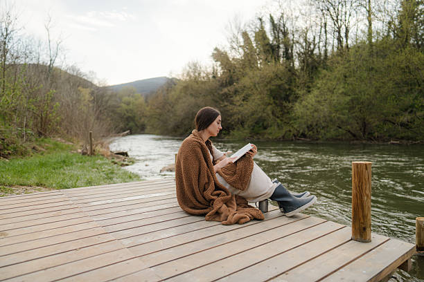 istock Reading a book and relaxing on the river dock 2217821478