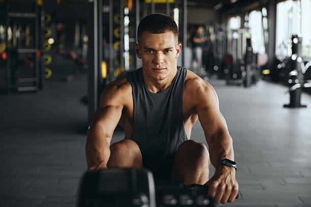 istock Concentrated attractive man working out on rowing device in contemporary gym 2217821695