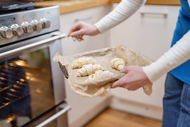 istock Baker removes freshly prepared rolls from the oven in a cozy kitchen setting during the afternoon 2217821753