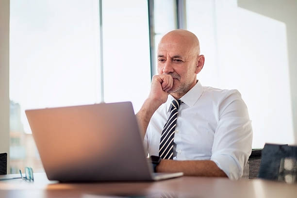 istock Mid aged businessman sitting at office desk and using his laptop for work 2217826832
