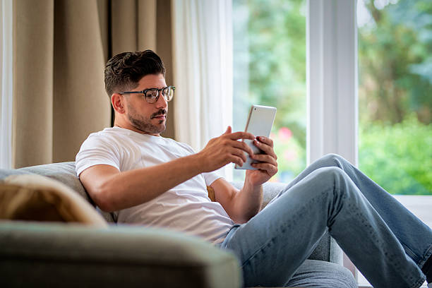 istock Mid aged man relaxing on the sofa at home and using his touchpad 2217827215