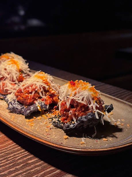 Gourmet food Beef Tartare appetizer canapes served on crispy rice crackers and topped with parmesan cheese