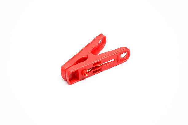 A single red plastic clothespin isolated on a white background, commonly used for hanging clothes or organizing small items.