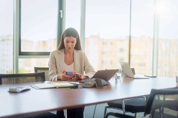 istock Woman sitting in a modern office and using smartphone and laptop 2217830297