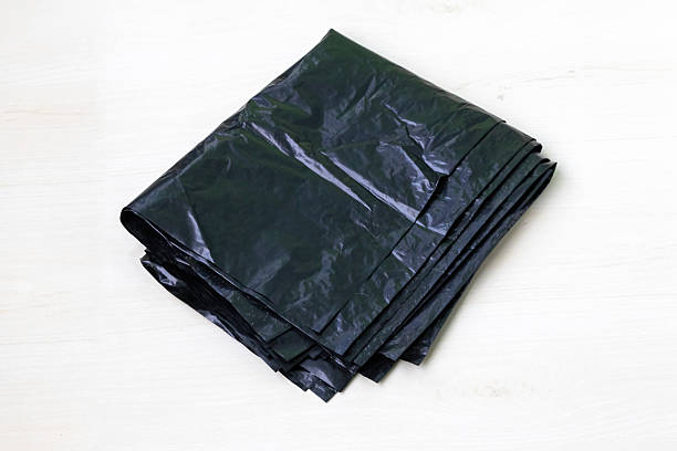 istock Black garbage bags isolated on white background; new, folded trash plastic bin bags; black polyethylene waste bags for containers. 2217833992