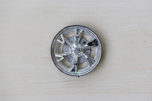 Broken plastic toy car wheel part on a wooden surface. Top view.