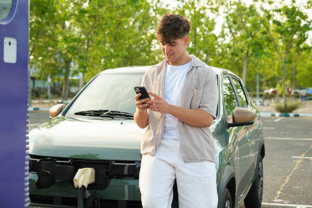 istock Young man using smartphone while charging electric car at charging station 2217834176