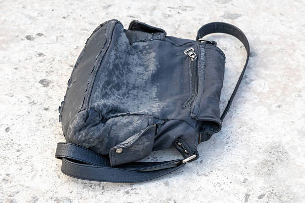 istock A worn black fabric woman's handbag lies on a concrete surface, torn and discolored from years of use. 2217834265