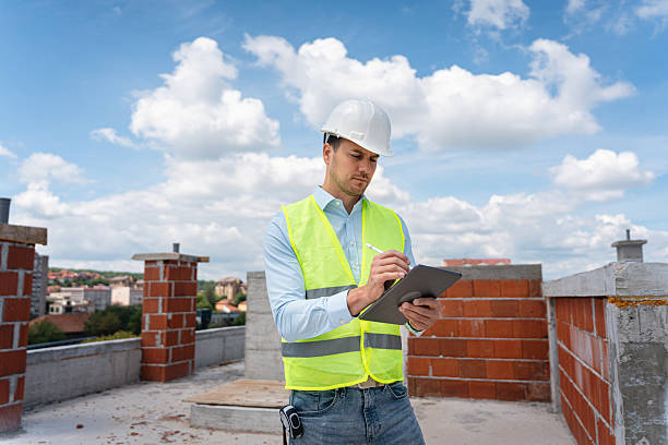 Engineer Reviewing Construction Plans on Site Using Digital Tablet During Inspection stock photo