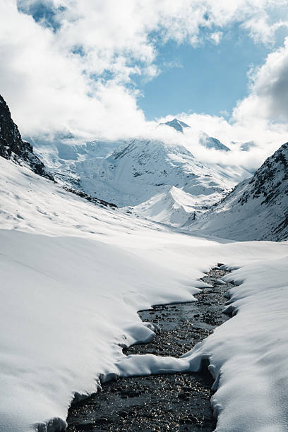 Stream in snowy valley below mountains, Pitztal Glacier, Otztal Alps