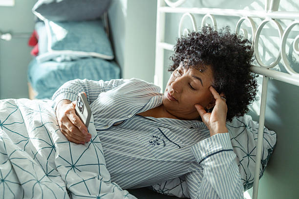 istock Woman in pajamas looking at her phone while lying in bed 2217841693