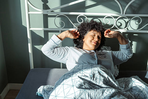 Woman stretching in bed during a bright sunny morning