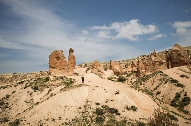 A hiker admires Cappadocia's surreal landscape. Wind and water sculpted these unique rock formations over centuries.