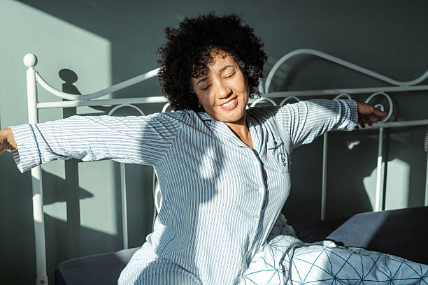 istock Woman stretching in bed during a sunny morning after waking up 2217842048