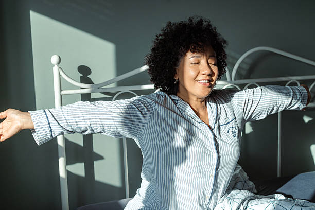 istock Woman stretching joyfully in bed during a sunny morning 2217842191