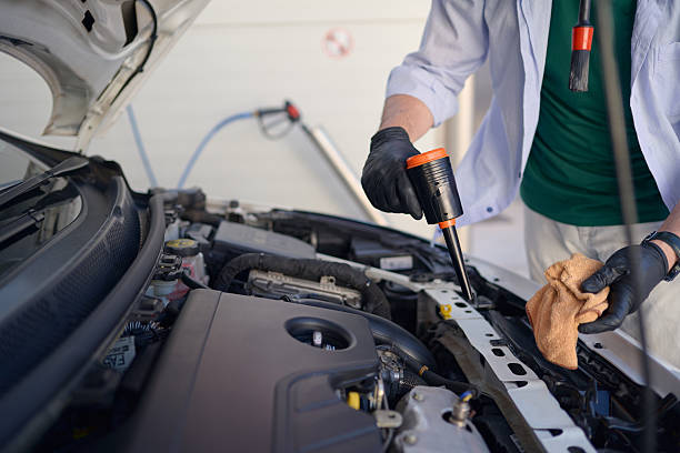 istock Mechanic performing maintenance check, applying lubricant to car engine 2217844692