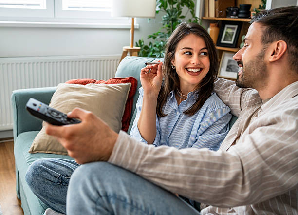 istock Young couple relaxing on sofa, watching tv and smoking marijuana joint 2217845662
