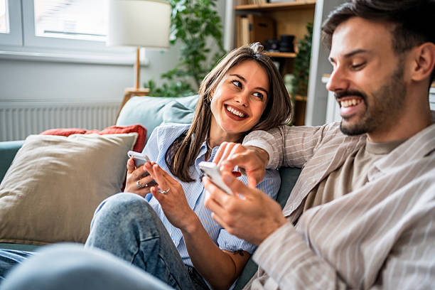 istock Young couple relaxing on sofa, browsing social media on smartphones 2217846453