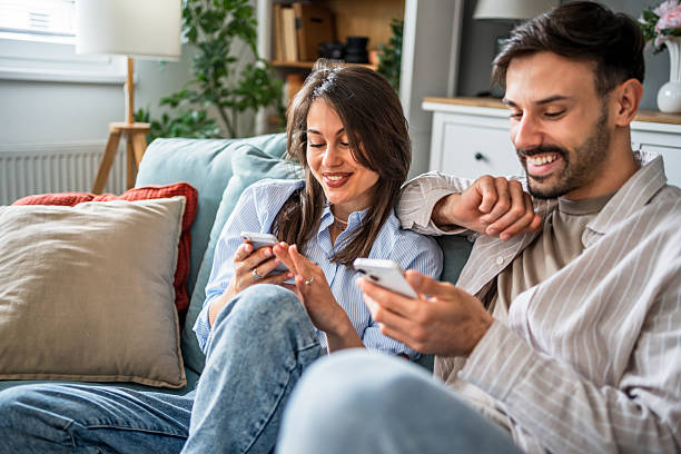 istock Young couple relaxing on sofa using smartphones at home 2217846529