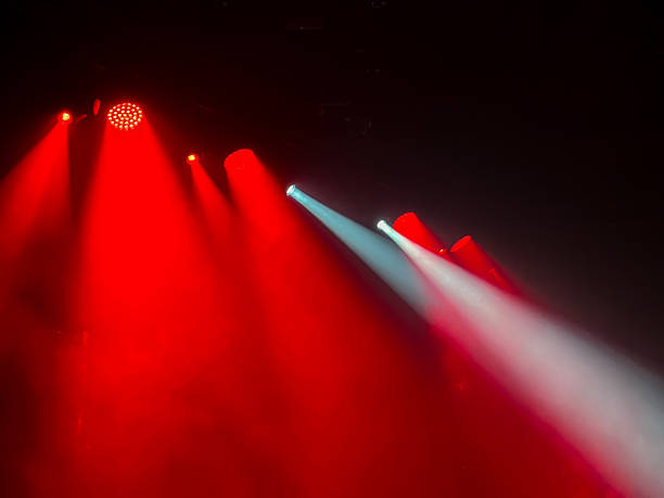 istock Vibrant dramatic red and white stage light beams cut through hazy darkness creating atmospheric lighting effect for concerts, parties, events, and shows. 2217846721