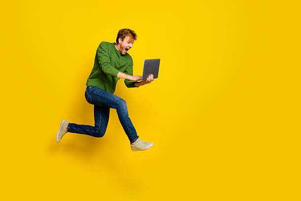 istock Full length photo of funky pretty guy dressed sweater jumping modern device empty space isolated yellow color background 2217846889