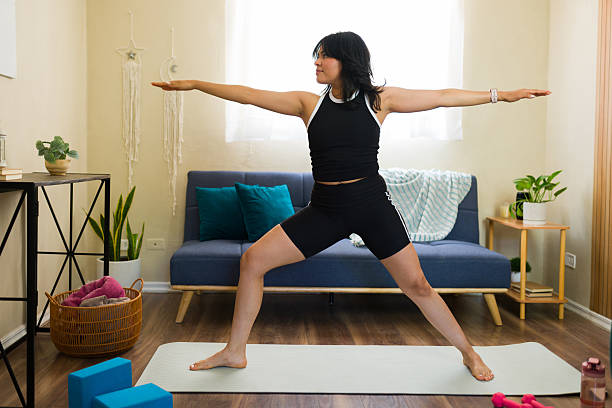 istock Woman practicing warrior two yoga pose at home 2217847129
