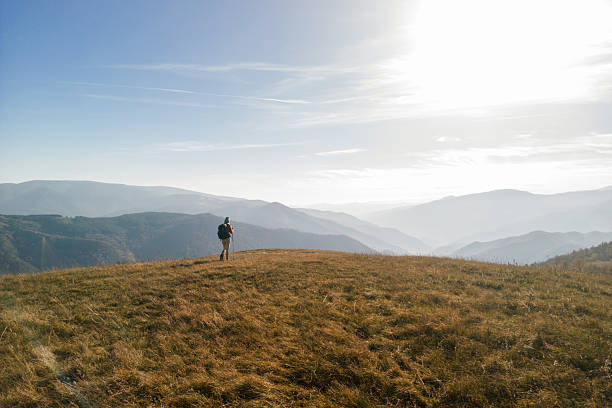 Woman hiking in the mountains. She is walking with hiking poles and carrying a backpack. She is enjoying the view. The nature is beautiful. Photo taken with drone