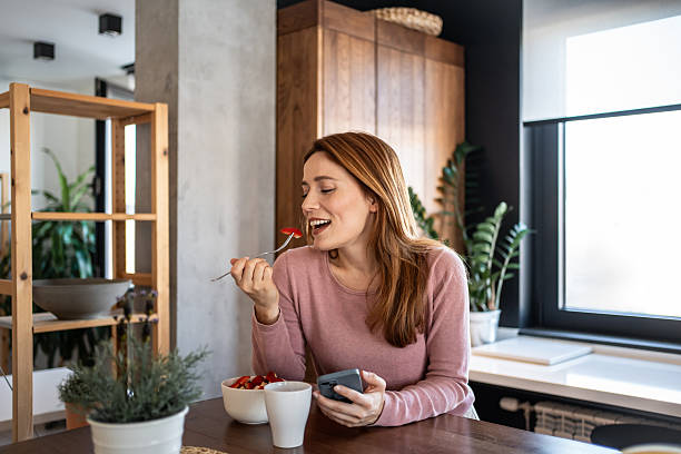istock Smiling woman enjoying breakfast and checking her phone 2217848534