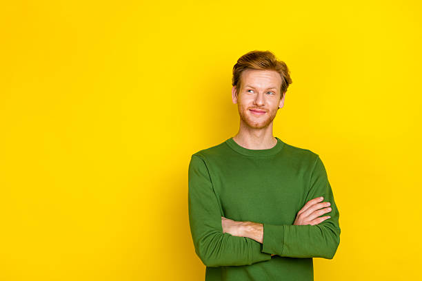 istock Photo of dreamy cute guy dressed green sweater arms folded looking empty space isolated yellow color background 2217849843
