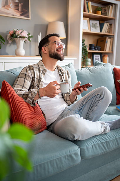 istock Young man relaxing on sofa, watching tv and drinking tea 2217850731