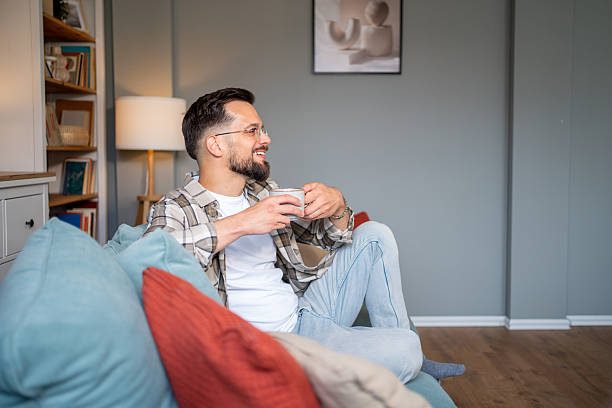 istock Young man relaxing on sofa with coffee, enjoying domestic tranquility 2217850967