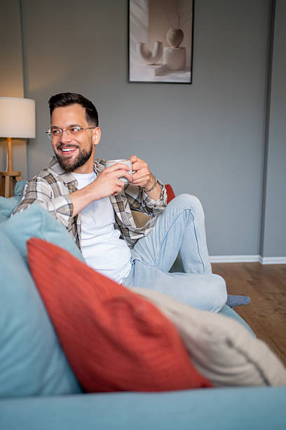 istock Young man relaxing on sofa with a cup of coffee at home 2217850985
