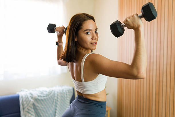 istock Active latin woman lifting weights at home for domestic training 2217853257