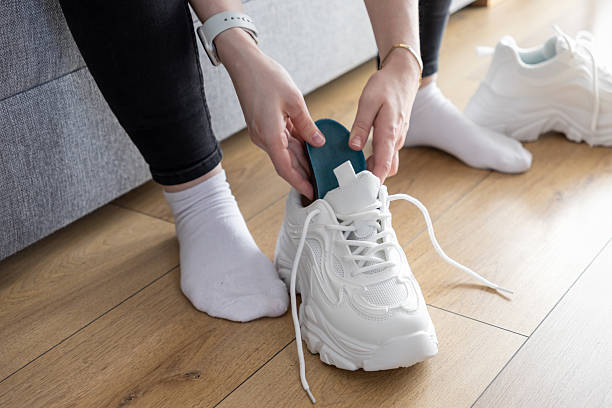 istock Person's hands inserting blue insole into white chunky training sneaker indoors, enhancing comfort and support for exercise 2217858962