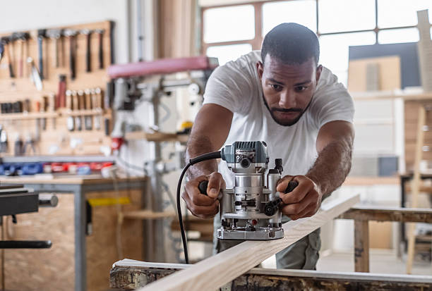 istock Focused Mid Adult Multiracial Carpenter Skillfully Using a Wood Router in a Bright Workshop 2217862934