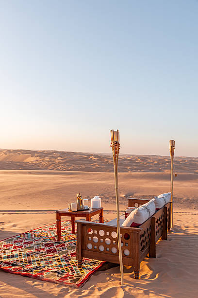 istock Sunset table and sofa arrangement, Arabic seating cushion and carpet corner set up in Liwa Desert Dune camp during sunset golden hour for romantic honeymoon 2217867933