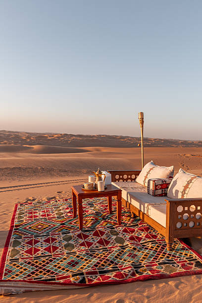 istock Sunset table and sofa arrangement, Arabic seating cushion and carpet corner set up in Liwa Desert Dune camp during sunset golden hour for romantic honeymoon 2217867936