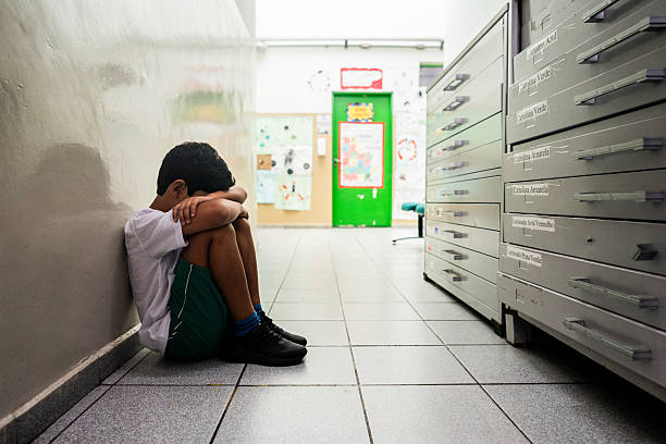 istock Sad child boy sitting on ground at school 2217870720