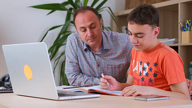 istock Father and teenage boy doing some homework together. 2217872772
