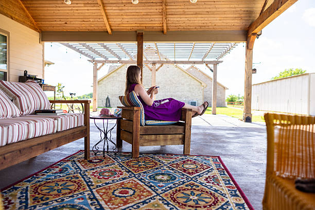 Young woman relaxing with hot tea on cozy terrace of wooden countryhouse. Autumn cozy day.