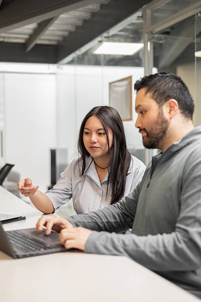 istock Young woman and man discussing data on computer screen together in modern office, collaborating on a project 2217877407