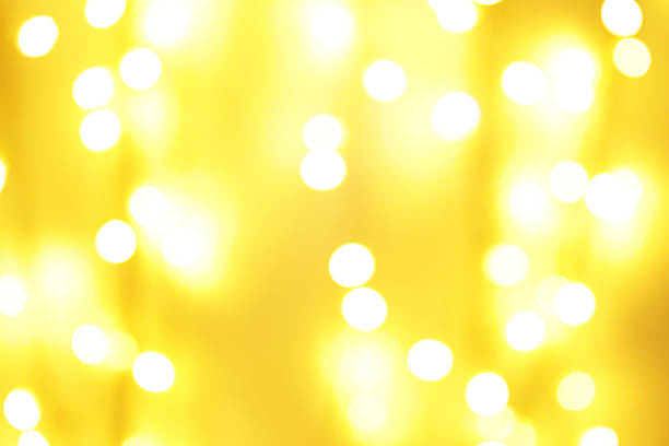 Golden-yellow festive background. Blurred bright holiday lights as a defocused backdrop