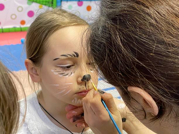 istock Cute girl waiting while makeup artist is making her creative carnival makeup 2217887712
