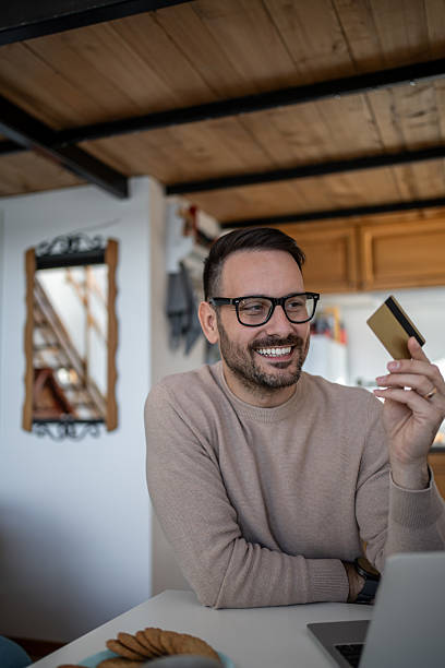 istock Smiling man making online payment using credit card at home 2217887735