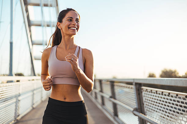 istock Smiling Woman Jogging on a Bridge During a Sunny Morning 2217888261