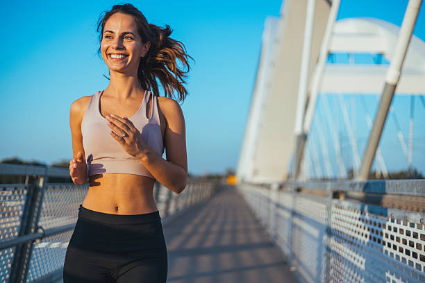 istock Smiling Woman Jogging on a Modern Bridge During a Sunny Day 2217888280
