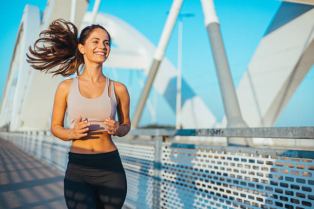 istock Smiling Young Woman Jogging on a Sunny Day on a Modern Bridge 2217888281